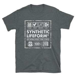 May include: A dark grey t-shirt with a white graphic design of a label that reads "Synthetic Lifeform&reg;" with the text "Off-World Incept Code: 010816" and a QR code.