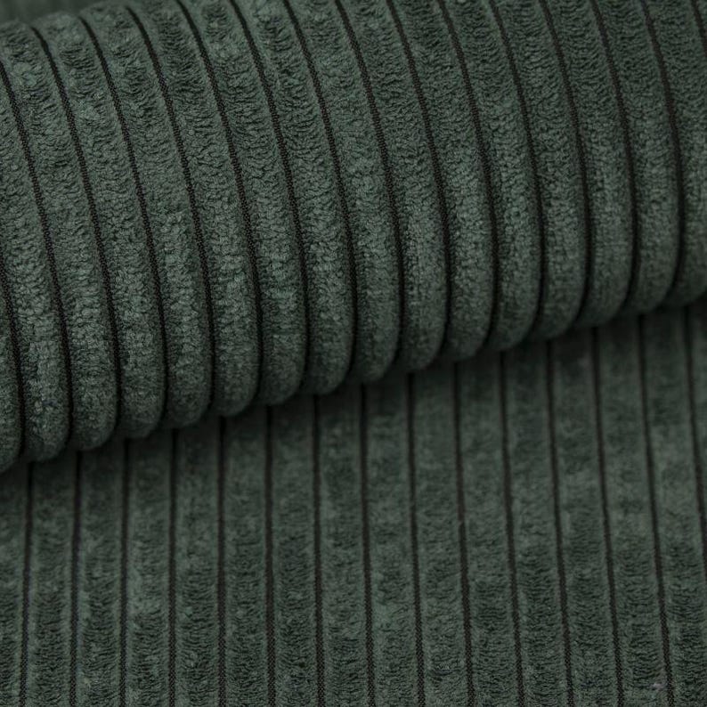 May include: Close-up of a textured, dark teal corduroy fabric. The fabric has vertical ridges and a soft, plush appearance. The color is a deep, muted green-blue, with subtle variations in tone.