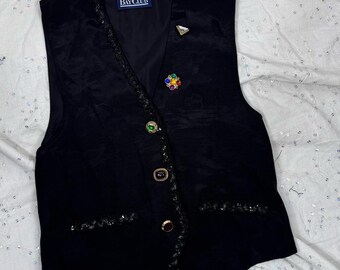 May include: Black vest with a beaded trim and decorative buttons. The vest has a label that reads "Bay Club".
