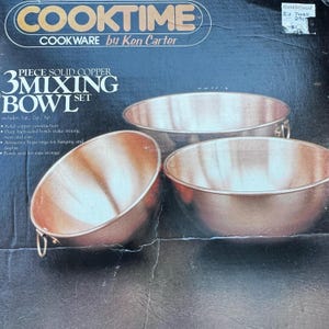 May include: A set of three solid copper mixing bowls. The bowls have a polished copper finish and brass rings for hanging. The packaging features the text "COOKTIME COOKWARE by Ken Carter" and "3 MIXING BOWL SET". Bowls nest for easy storage.