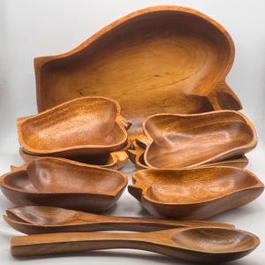 May include: A white ceramic mug with a black handle and the text "But First, Coffee" in a bold, black font. The mug is set against a blurred background, suggesting a cosy setting.