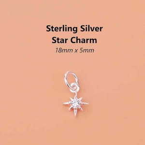 May include: A sterling silver star charm with a sparkling centre stone. The charm measures 18mm x 5mm. The text "Sterling Silver Star Charm" is displayed above the charm on a peach background.