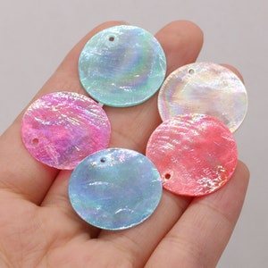 Peut inclure: Assortiment de paillettes rondes en coquille irisées dans différentes couleurs pastel, notamment rose, bleu et blanc. Chaque paillette a un petit trou pour le passage d'un fil.