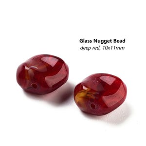 May include: Two deep red glass nugget beads, each measuring 10x11mm. The beads have a slightly irregular shape and a glossy finish.