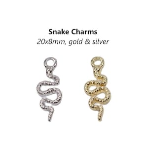 Puede incluir: Dos abalorios de serpiente, uno dorado y otro plateado, cada uno mide 20x8mm. Los abalorios tienen forma de serpiente con una superficie texturizada.
