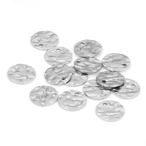 May include: A collection of silver-toned metal round charms with a textured surface. Each charm has two small holes for attaching to jewelry or other crafts.