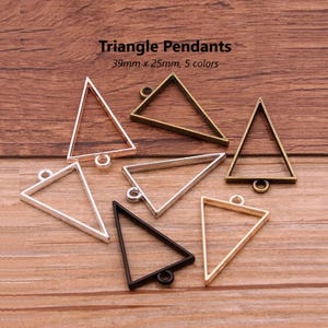 May include: Six triangle-shaped metal pendants with a loop at the top for hanging. The pendants are in various colours, including silver, gold, black, and bronze. The pendants are 39mm x 25mm.