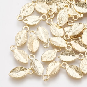 May include: A pile of gold-coloured metal leaf charms with a loop at the top. The leaves have a textured surface.