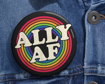 Peut inclure: Un bouton noir avec un motif arc-en-ciel et le texte "ALLY AF" en blanc.
