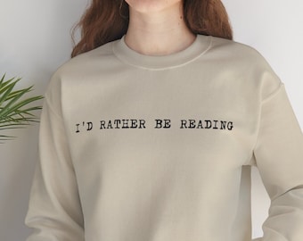 May include: A beige sweatshirt with the text "I'd rather be reading" in black typewriter font.