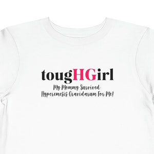 Puede incluir: Camiseta blanca para niño pequeño con texto negro que dice "toughHGirl My Mommy Survived Hyperemesis Gravidarum For Me!" El "HG" de la palabra "toughHGirl" es rosa.