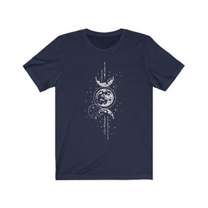 May include: A navy blue t-shirt with a white graphic of three moons in different phases, surrounded by stars and a geometric design.