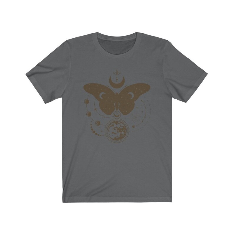 May include: A dark gray t-shirt with a brown graphic of a butterfly with a moon and stars. The butterfly is surrounded by a circle of small moons and stars.