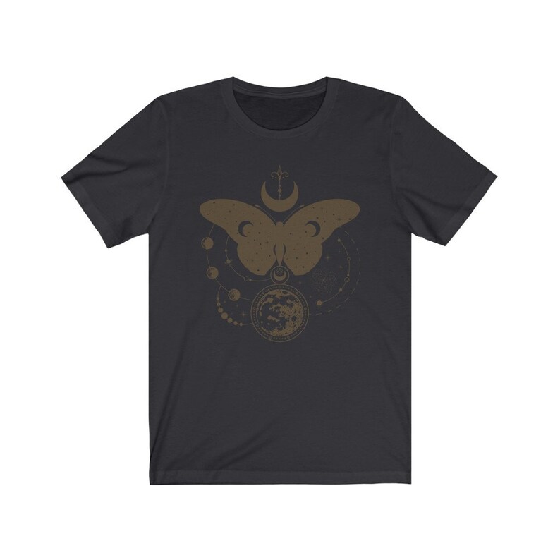 May include: A dark gray t-shirt with a gold-colored design of a butterfly with a crescent moon and stars. The design is centered on the shirt.
