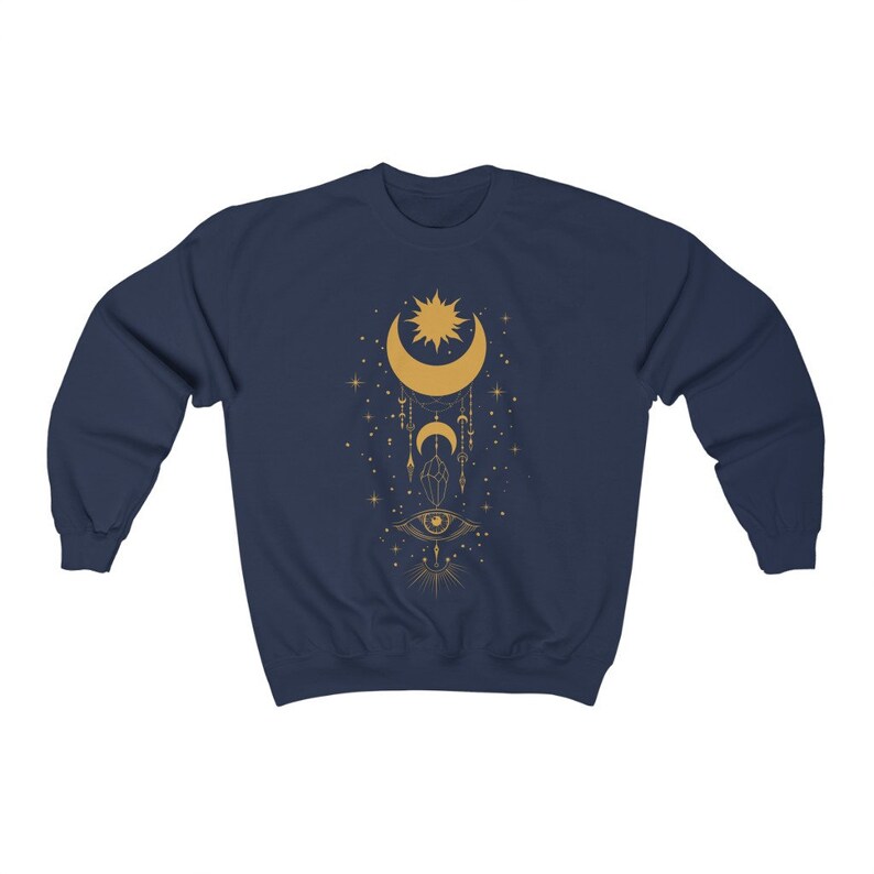 May include: Navy blue sweatshirt with a gold celestial design featuring a crescent moon, sun, stars, and an eye.