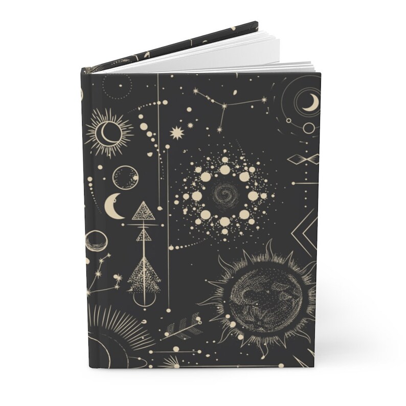 May include: A black journal with a gold celestial pattern. The pattern includes moons, stars, suns, and geometric shapes.