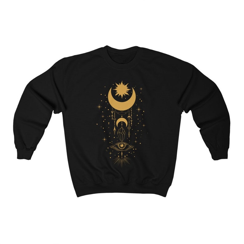 May include: Black sweatshirt with a gold celestial design featuring a crescent moon, sun, and eye. The design also includes stars, crystals, and feathers.