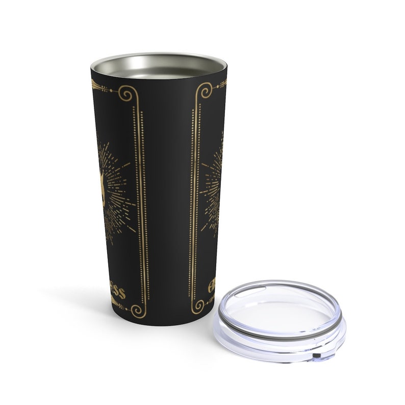 May include: A black stainless steel tumbler with a gold design featuring a sunburst and the word "Happiness". The tumbler has a clear lid.