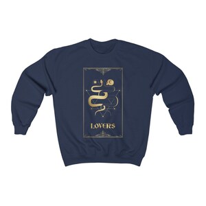 Puede incluir: Sudadera azul marino con un gr&aacute;fico dorado de una serpiente y la palabra "LOVERS" en un marco decorativo.