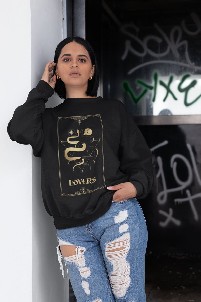 Puede incluir: Sudadera negra con un gr&aacute;fico dorado de una serpiente y la palabra "LOVERS" en la parte delantera.