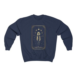 Op de afbeelding: Donkerblauw sweatshirt met een gouden illustratie van de tarotkaart de Hogepriesteres. De kaart toont een vrouw die met haar armen gespreid staat, omringd door sterren en manen.