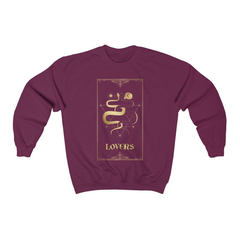 Puede incluir: Sudadera color burdeos con un gr&aacute;fico dorado de una serpiente y formas geom&eacute;tricas. El gr&aacute;fico est&aacute; rodeado por un marco dorado y la palabra "LOVERS" est&aacute; escrita debajo del gr&aacute;fico.