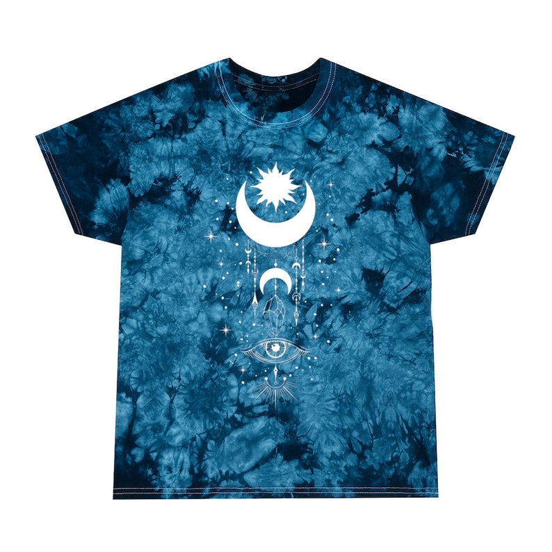 May include: A blue tie-dye t-shirt with a white graphic of a crescent moon, sun, and eye with geometric designs. The graphic is centered on the shirt.