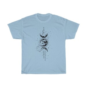 May include: Light blue t-shirt featuring a black graphic of a celestial design. The design includes phases of the moon, stars, and geometric lines. The shirt is made of a soft material.