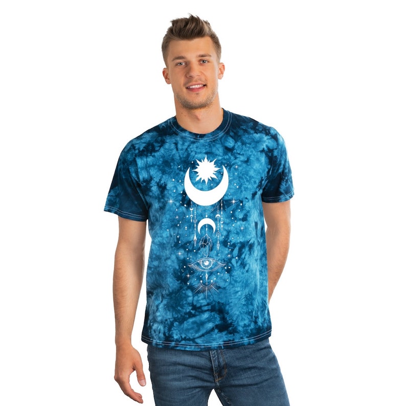 May include: A blue tie-dye t-shirt with a white crescent moon, sun, and eye design. The design also includes stars and other celestial symbols.