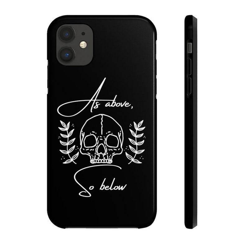 Op de afbeelding: Zwarte telefoonhoes met een witte schedel en de tekst "As above, so below".