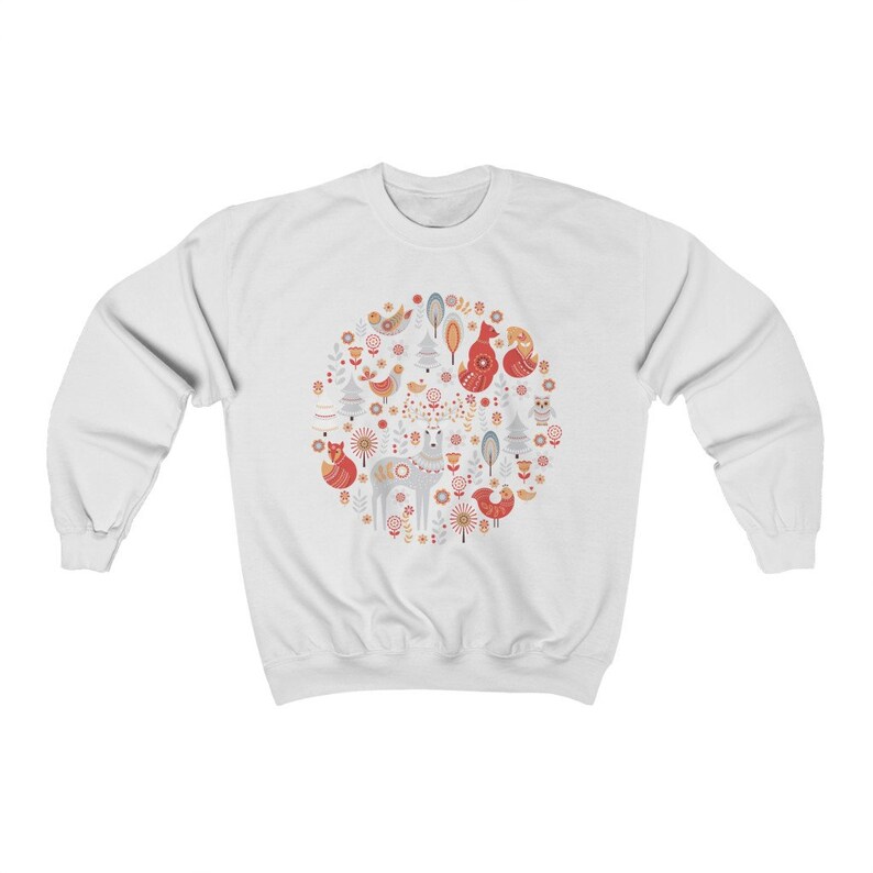 May include: White sweatshirt with a circular design featuring a variety of woodland animals, including foxes, birds, and deer, in a Scandinavian folk art style. The design is in shades of red, orange, blue, and gray.