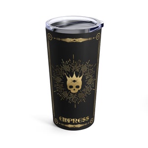 May include: A black stainless steel tumbler with a gold design featuring a skull with a crown and the word "Empress".