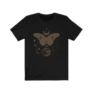 May include: Black t-shirt with a brown graphic of a butterfly with a moon and stars around it.