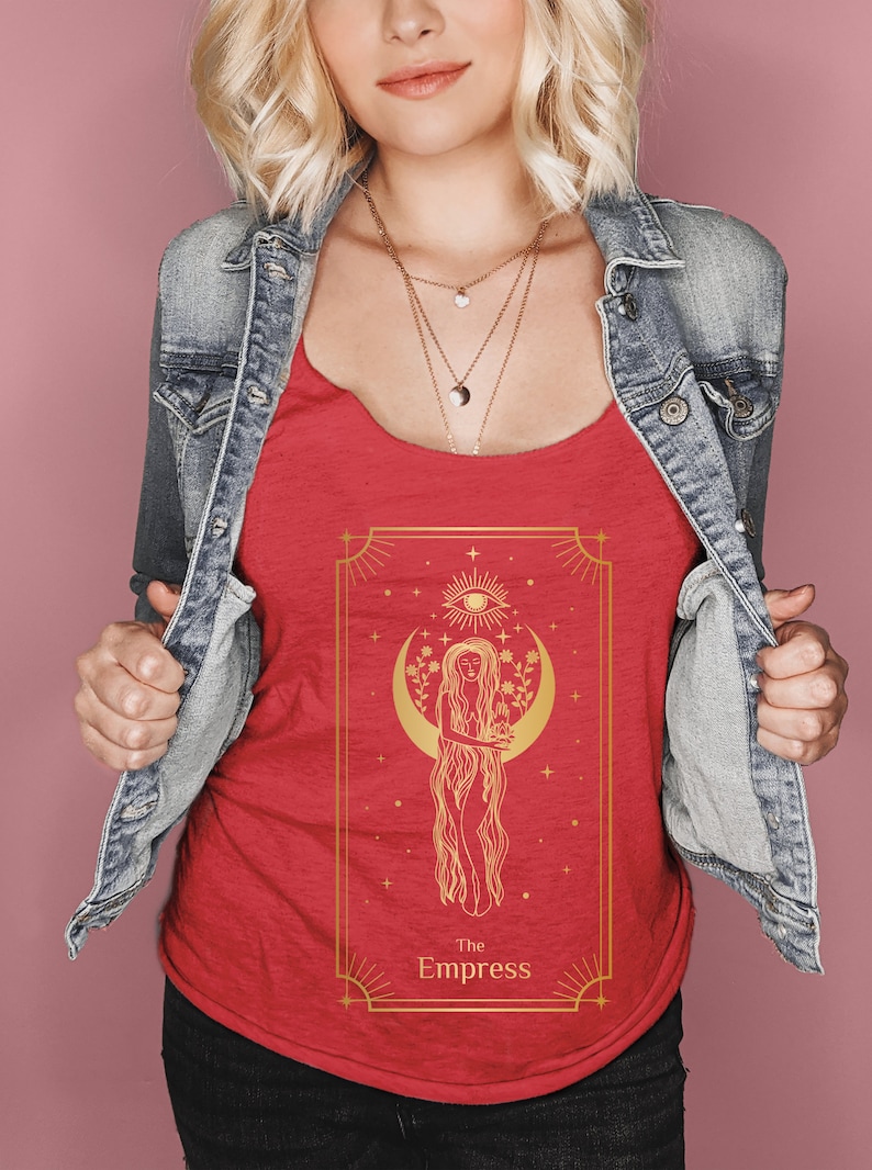 Puede incluir: Un top rojo sin mangas con una ilustraci&oacute;n dorada de la carta del tarot de la Emperatriz. La carta representa a una mujer de pie en una luna creciente con una corona de flores y un tercer ojo. El texto "La Emperatriz" est&aacute; impreso debajo de la imagen.