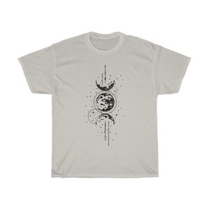 May include: A light gray t-shirt featuring a black graphic of the phases of the moon. The design includes crescent moons, a full moon, stars, and lines. The shirt is made of a soft material.