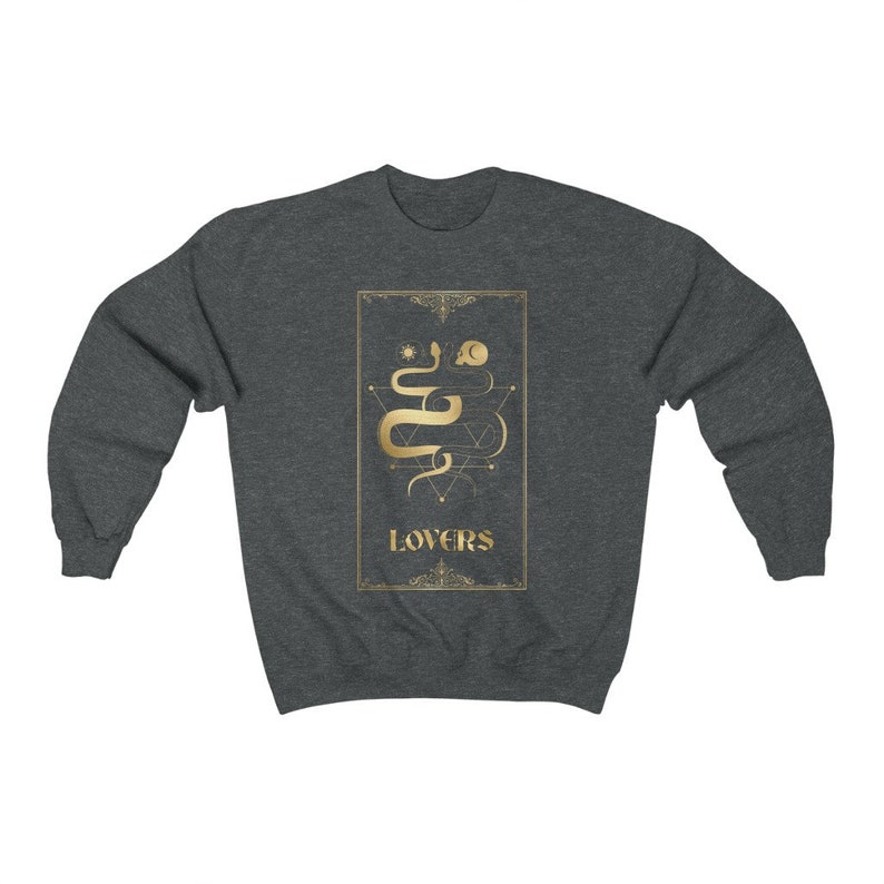 Puede incluir: Una sudadera gris oscuro con un gr&aacute;fico dorado de una serpiente y formas geom&eacute;tricas. El gr&aacute;fico est&aacute; rodeado por un marco dorado y la palabra "LOVERS" est&aacute; impresa debajo del gr&aacute;fico.