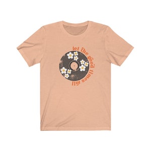 K&ouml;nnte beinhalten: Ein pfirsichfarbenes T-Shirt mit einem Vintage-Schallplatten-Design mit wei&szlig;en G&auml;nsebl&uuml;mchen und dem Text "Let the good times roll."
