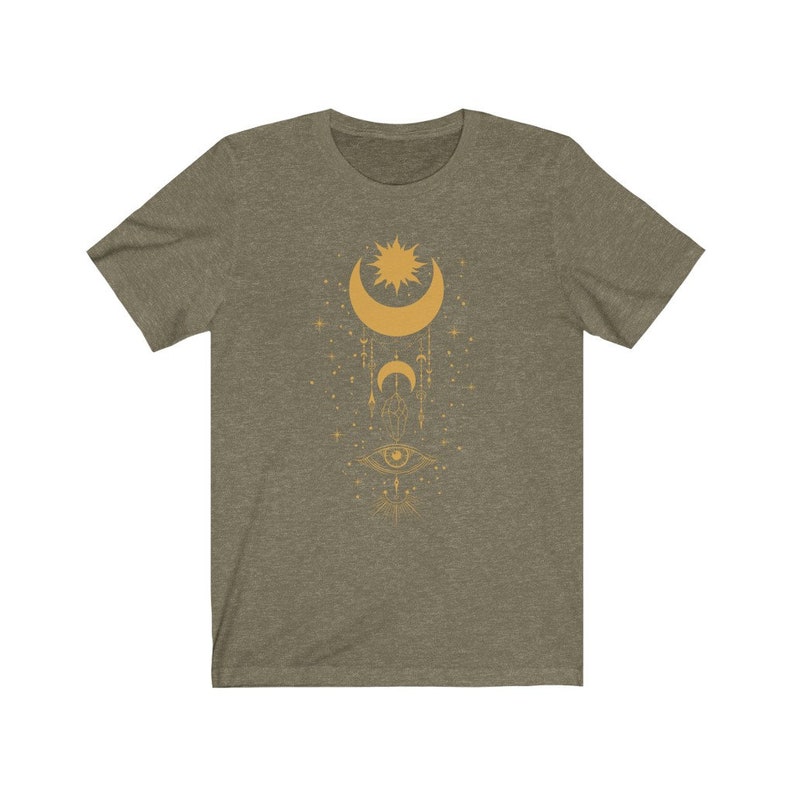 May include: A green t-shirt with a gold design of a crescent moon, sun, and eye with geometric shapes and stars.