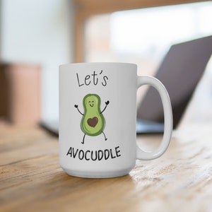 May include: White ceramic coffee mug with a green avocado illustration and the text "Let's Avocuddle".