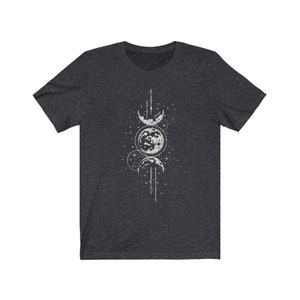 May include: A dark heather grey t-shirt with a white moon phases design. The design features three crescent moons and a full moon with stars and a line of small circles.