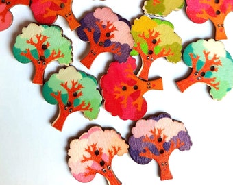 Puede incluir: Surtido de botones de madera coloridos con forma de árboles. Cada botón tiene dos agujeros y presenta un diseño pintado único con diferentes colores y patrones.