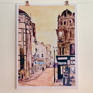 May include: A watercolor painting of a street scene with a clock tower in the background. The buildings are painted in shades of brown and yellow, and the street is empty except for a single figure walking in the distance.