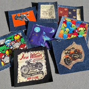 May include: A collection of denim patches with various designs. Some patches feature cartoon characters, motorcycles, and patriotic themes. One patch has the text "Iron Wheels Legendary Racers Club Ride 2 Live".