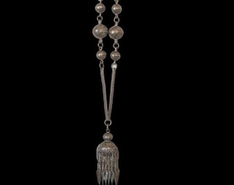 Puede incluir: Un collar de plata con un colgante de borla y cuentas redondas. El collar está hecho de una cadena con un diseño delicado.