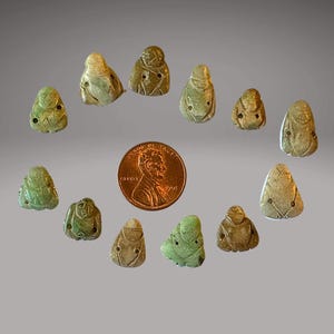 May include: A collection of 12 small, green and white jade carvings of figures. The carvings are about the size of a US penny.