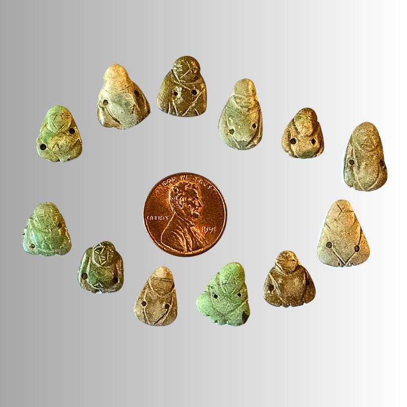 May include: A collection of 12 small, green and white ceramic figurines. The figurines are shaped like people and have a variety of poses. They are arranged in a circle around a penny.