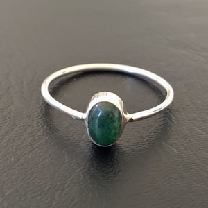 May include: A silver ring with a green oval gemstone.
