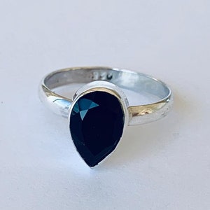 May include: A silver ring with a black pear-shaped gemstone.