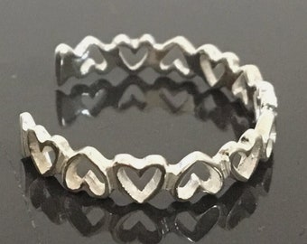 May include: Silver toe ring with a delicate design of interlocking hearts.