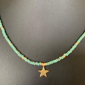 May include: A turquoise and gold beaded necklace with a gold star pendant.